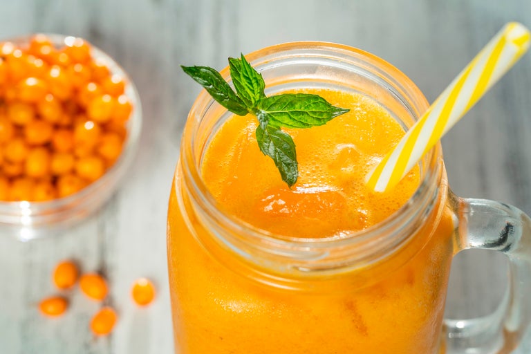 Glas havtornjuice med mynta och sugrör