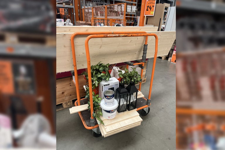 Kundvagn i en järnaffär med trä, färg, dekorationer och lyktor