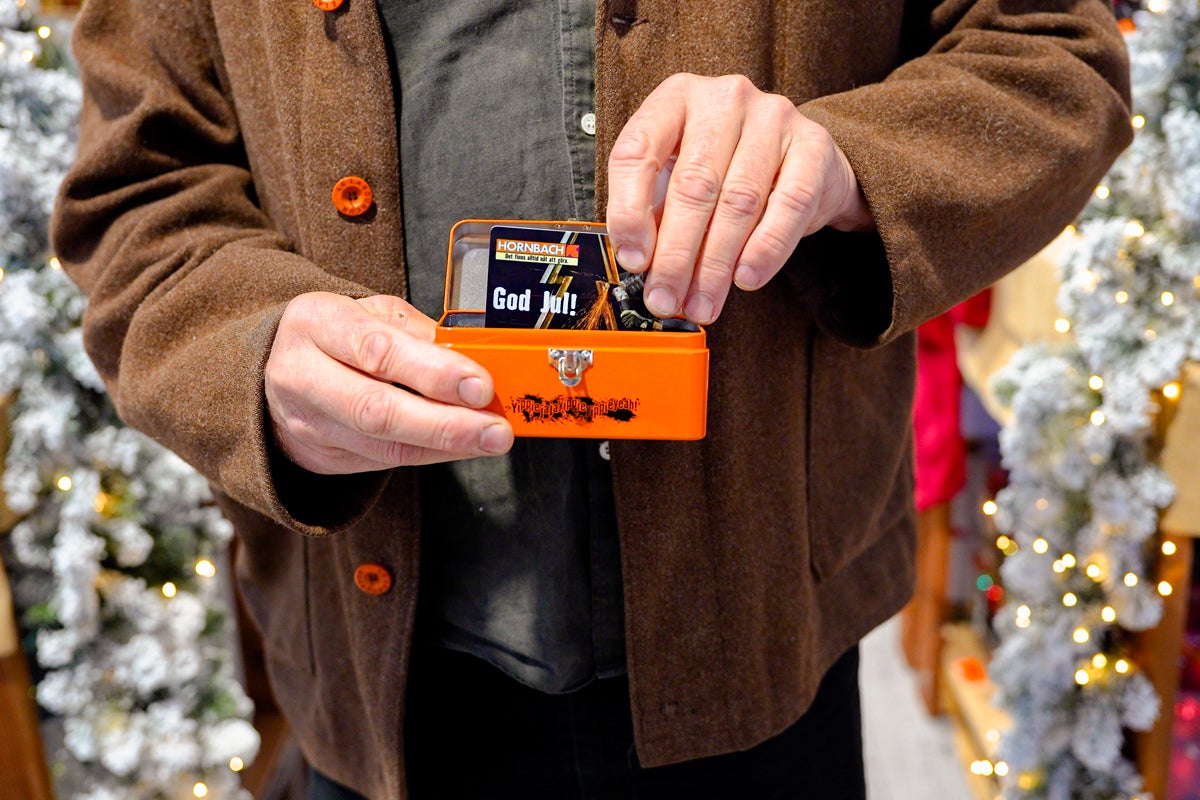 Man håller en orange metallåda med julkort