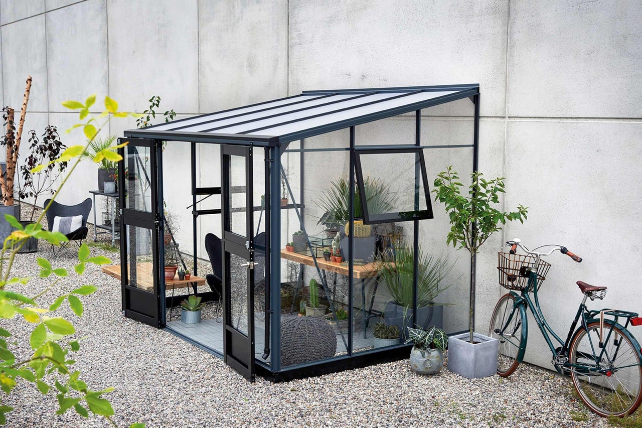 Växthus med växter och en cykel i trädgården
