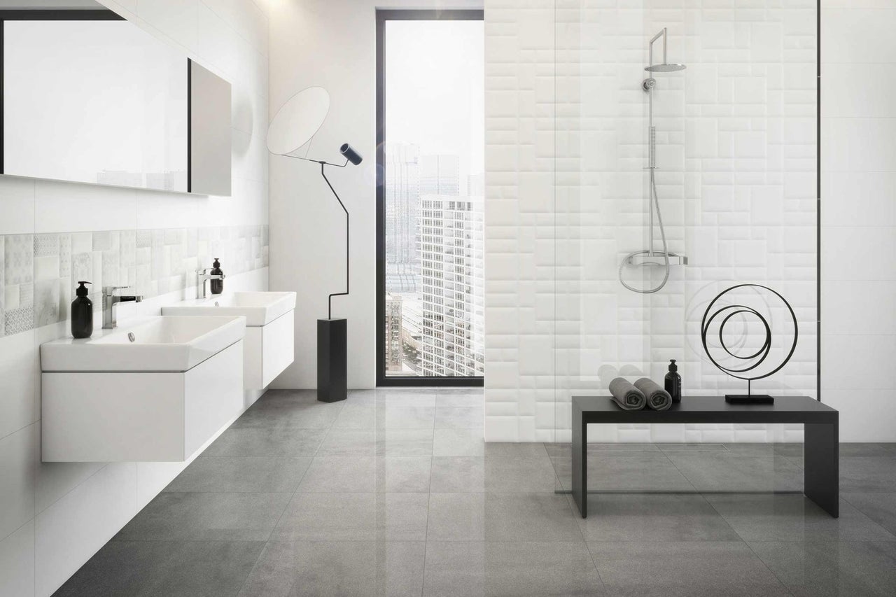 Ljust badrum med handfat, spegel, dusch och gråa plattor