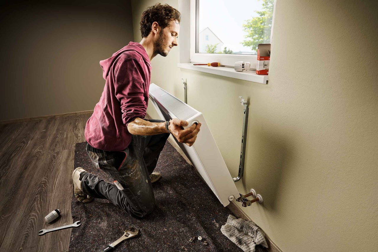 Man installerar element på en vägg i ett rum.