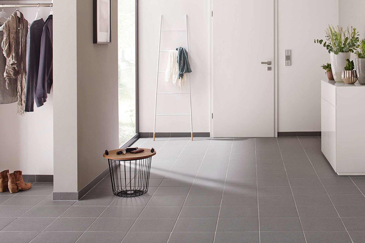 Ljus hall med garderob, stegliknande hylla och grått klinkergolv.
