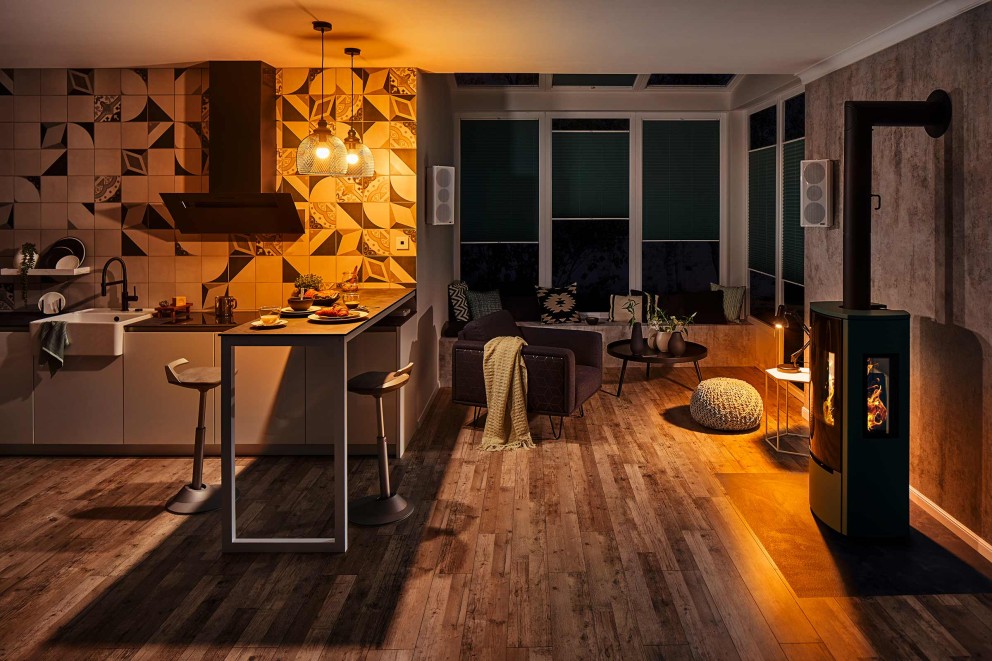 Vardagsrum med kök, sittgrupp och kamin i ljus miljö