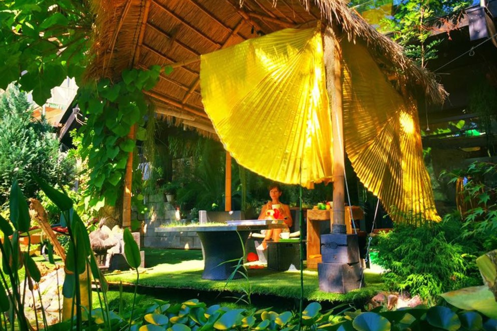 
				Nästan som på Bali: Sabine i skuggan under taket av palmblad.

			