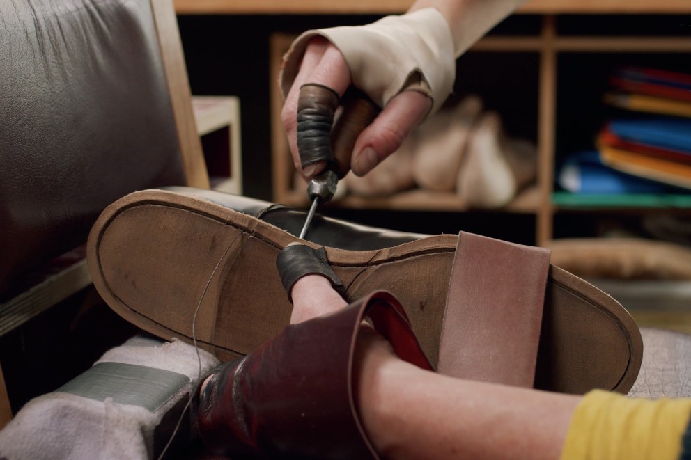
				Gabriele Braun arbetar med en syl på en måttbeställd sko

			
