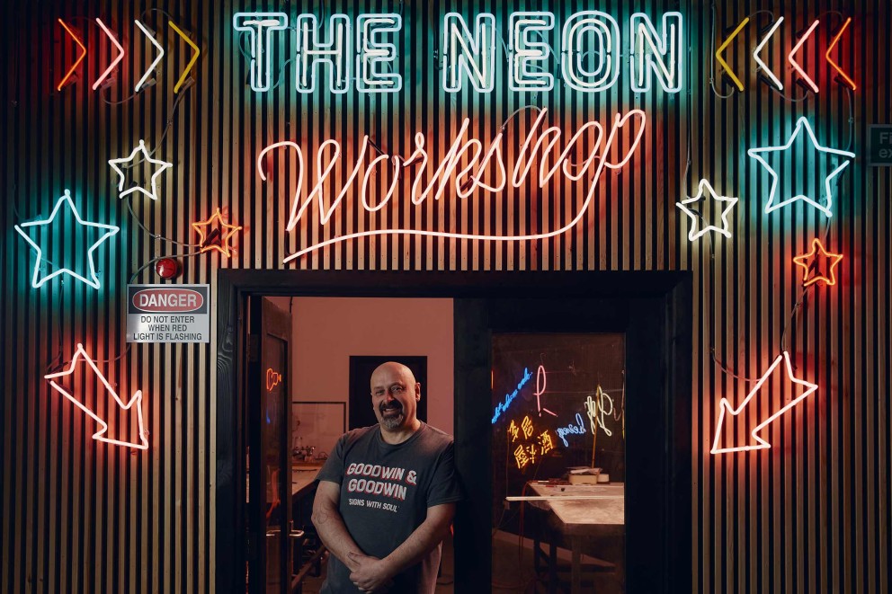 Ingången till The Neon Workshop med neonreklamer och en varningsskylt