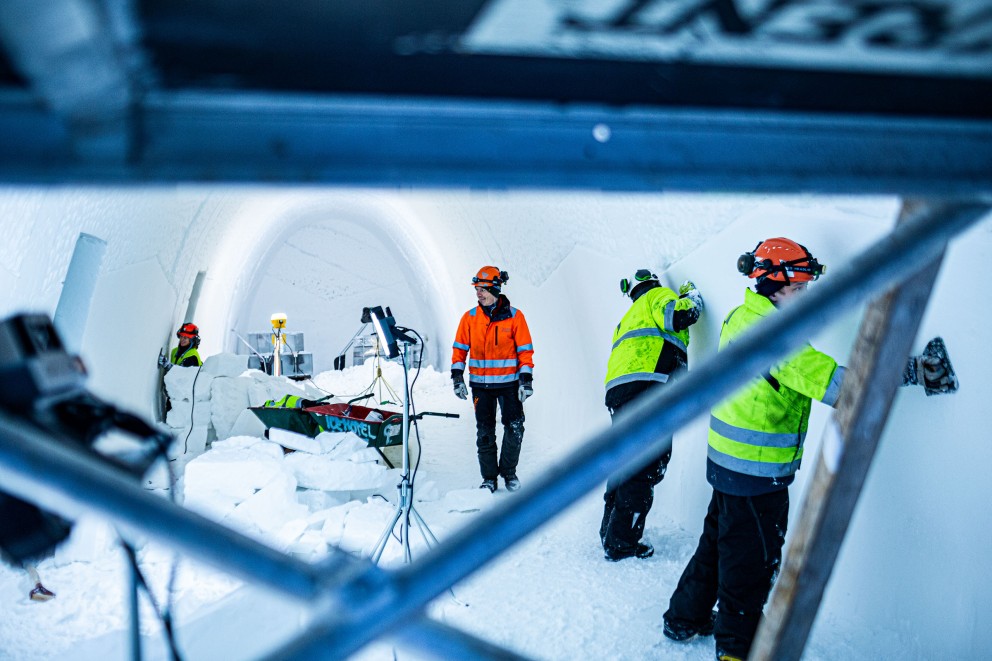 
				Arkitekt Luca Roncoroni i ett avlångt rum i Ishotellet. Två hantverkare slipar isväggarna.

			