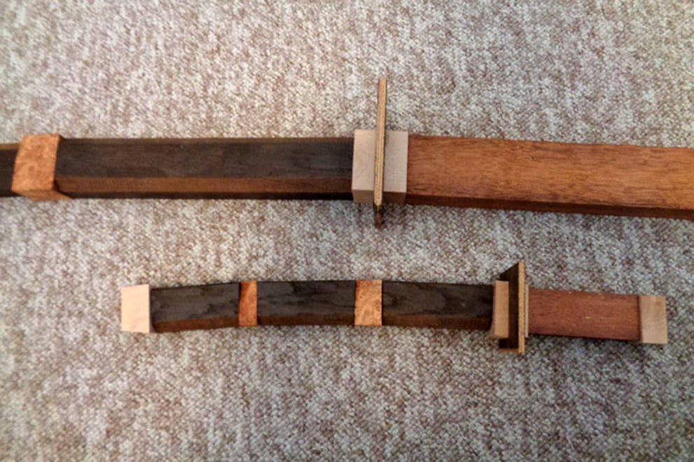 
				Limmade svärd i olika träslag.

			