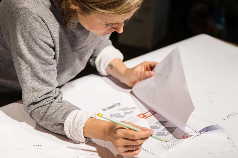 En kvinna tittar på byggplaner med en penna