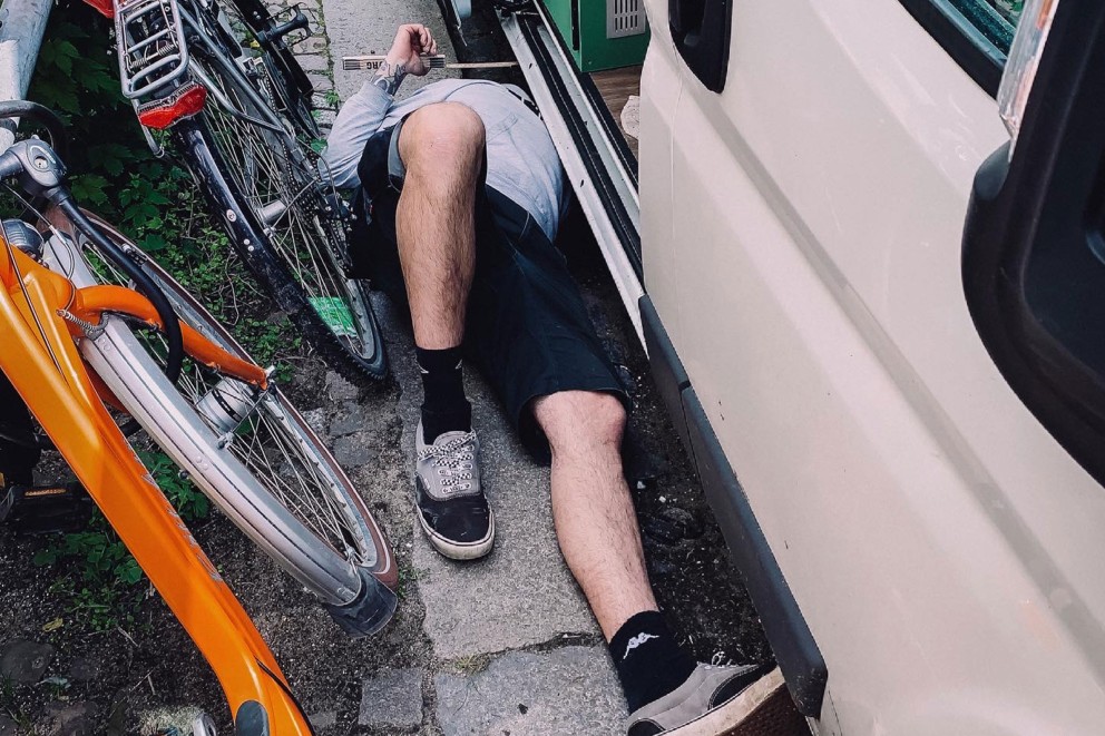 Thomas ligger på rygg på trottoarkanten mellan cyklar och bilen. Thomas ligger på rygg på trottoarkanten mellan cyklar och bilen.
