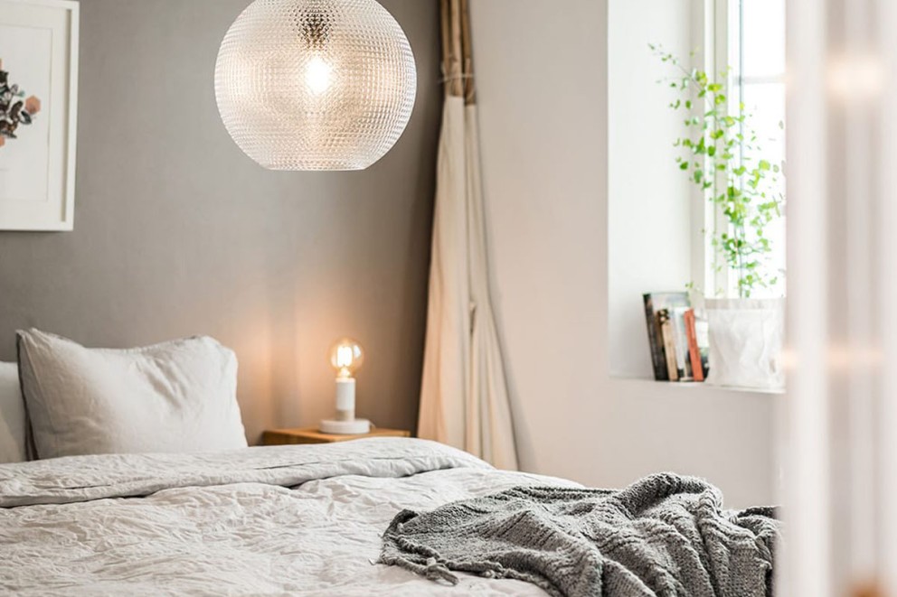 Sovrum med säng, sängbord och rund hänglampa