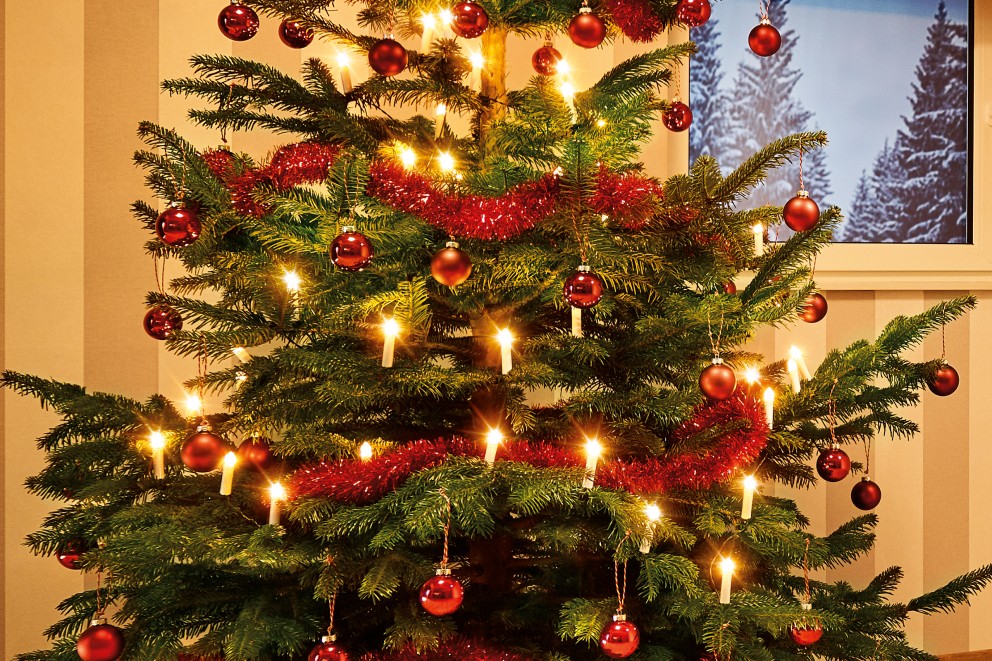 Dekorerad julgran med julgranskulor, glitter och ljus