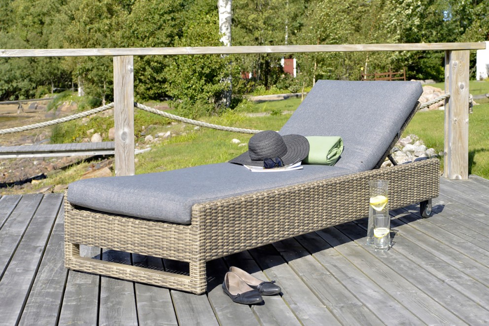 Trädgårds solstol i rotting med grå stoppning på en träterrass