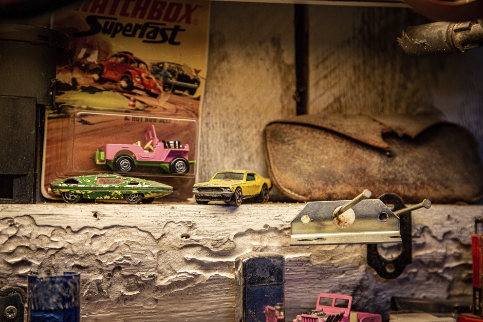 
				Gamla leksaksbilar och prylar pryder väggarna i verkstaden

			