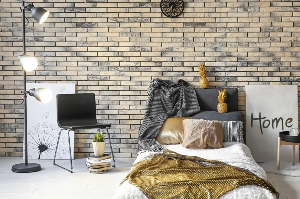 Sovrum med säng, stol, golvlampa och dekorativ tegelvägg