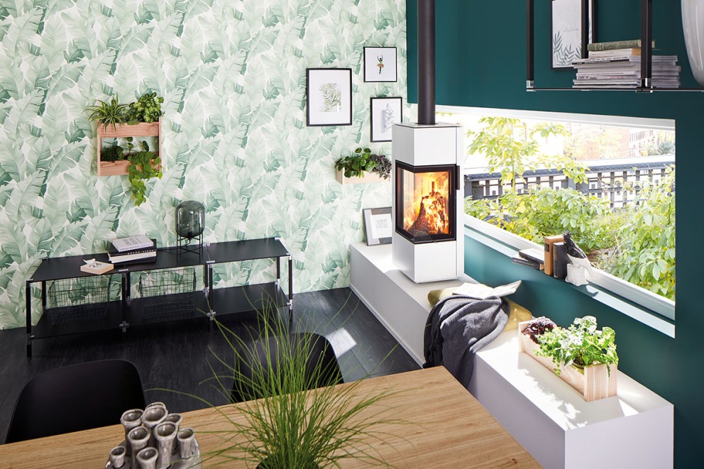 Vardagsrum med öppen spis, hylla, växter och botanisk tapet