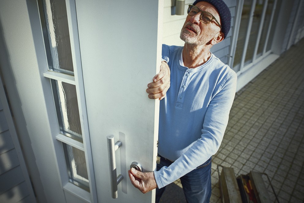Man öppnar en ytterdörr med glasinsatser och ett metallhandtag