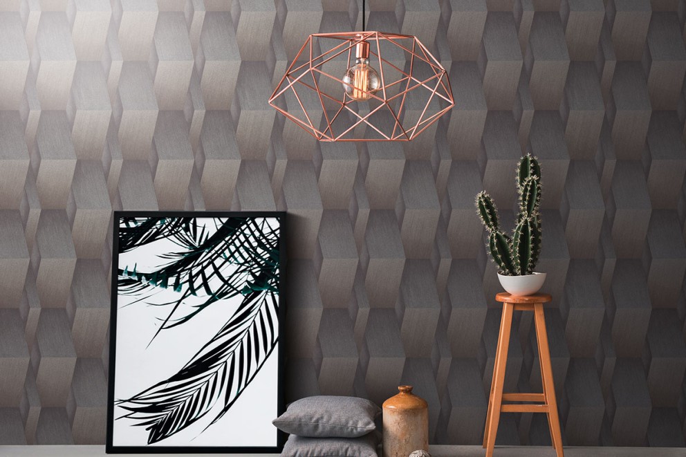 Dekorativ inredning med geometrisk tapet, lampa, växt, bild och kuddar