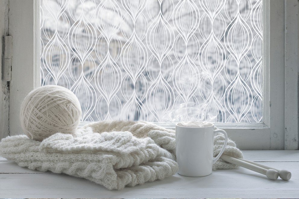 Bilden visar en stickning som ligger på en vit fönsterkarm vid ett fönster med dekorplast på rutan. Utanför fönstret är det vinter och snö. Bilden visar en stickning som ligger på en vit fönsterkarm vid ett fönster med dekorplast på rutan. Utanför fönstret är det vinter och snö.