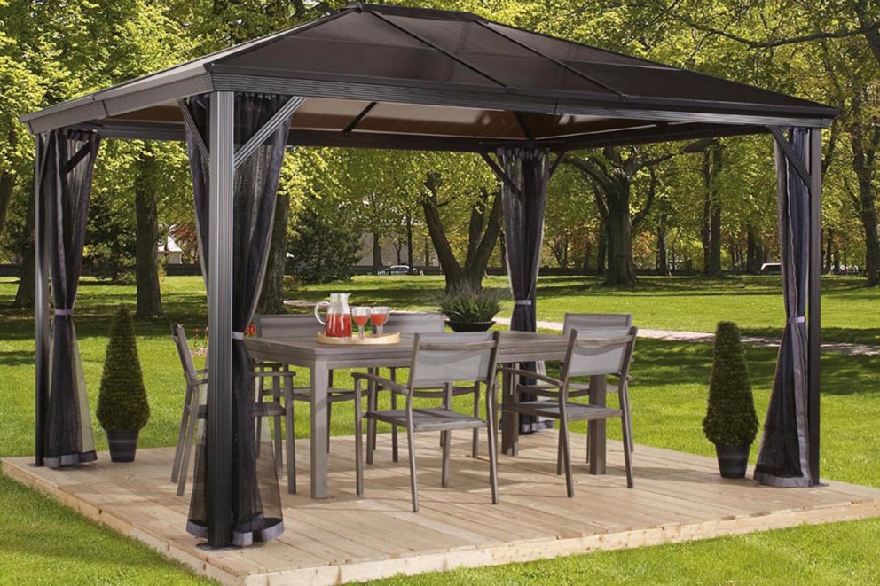 Paviljong med bord och stolar på en träterrass i trädgården