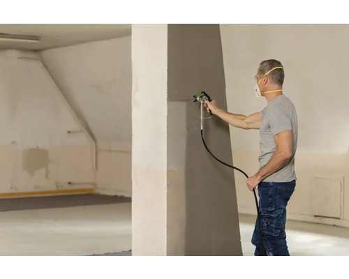 Man målar vägg med färgspruta