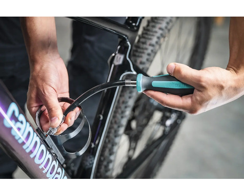 En person fäster en flaskhållare på en cykel med en skruvmejsel.