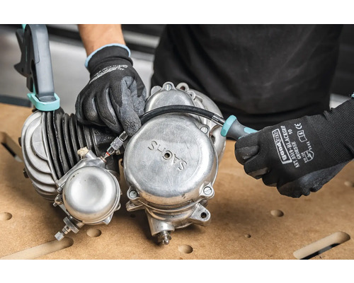 Händer med handskar som arbetar på en Sachs-motor med en skruvmejsel