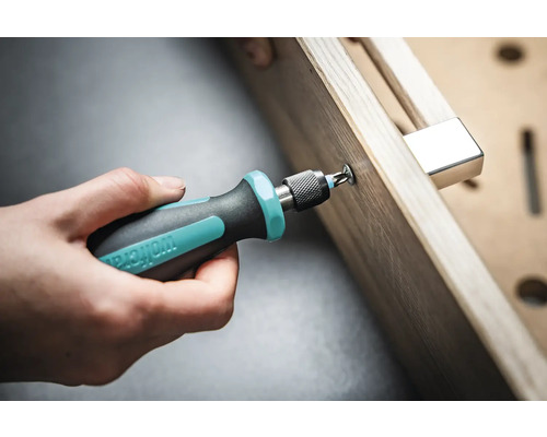 En hand skruvar en skruv med en skruvmejsel i ett arbetsstycke.