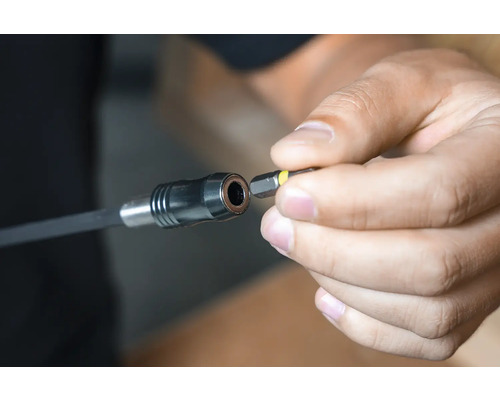 En person sätter in en skruvbits i en bitshållarförlängare.