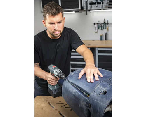 En man använder en sladdlös skruvdragare för reparationsarbeten på en komponent.