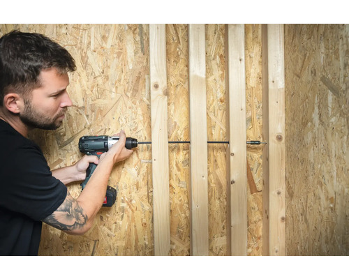 Man skruvar fast träribbor på en spånskiva med en sladdlös skruvdragare