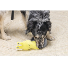 En hund leker med en gul snigelformad hundleksak på en matta.