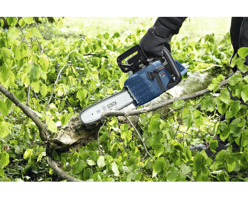 En person sågar en gren med en Bosch motorsåg.