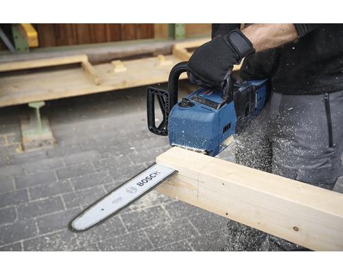 En person sågar en träplanka med en Bosch batteridriven motorsåg.