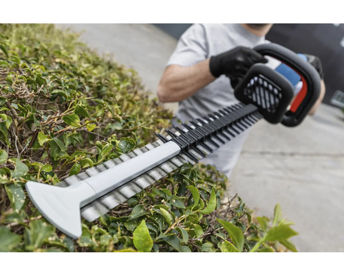 En person klipper en häck med en häcksax.