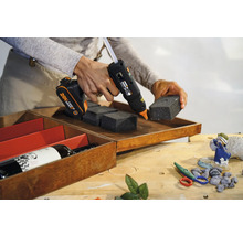 Batteridriven limpistol fäster skumbitar i en trälåda.