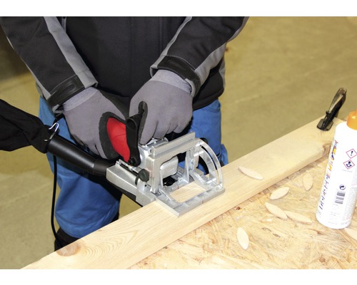 En person använder en lamellfräs på en träplanka.