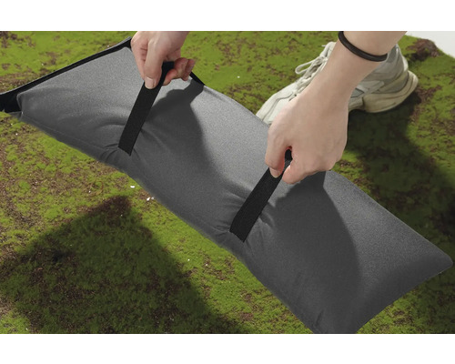 Grå sandsäck med handtag på grön yta