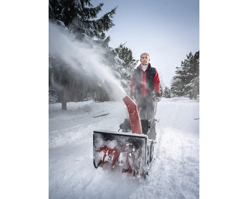 Man använder en snöslunga för att röja snö på en snötäckt väg
