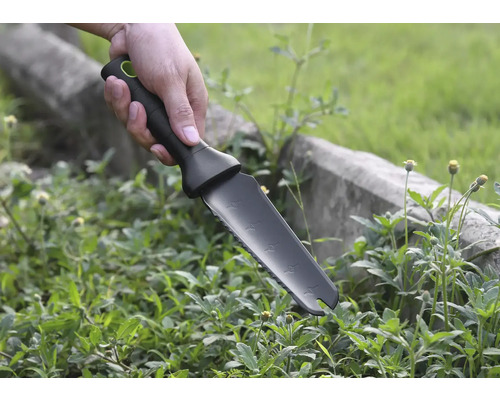 Hand håller trädgårdskniv för att rensa ogräs.