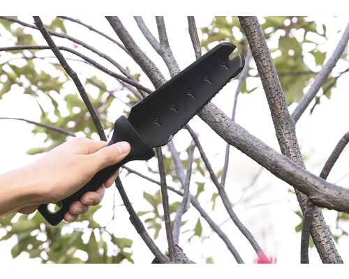 En hand håller en multifunktionell trädgårdsyxa som används på en gren