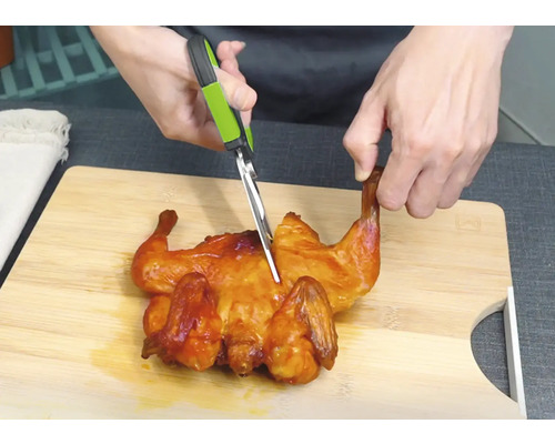 Kyckling skärs med en kökssax på en skärbräda.