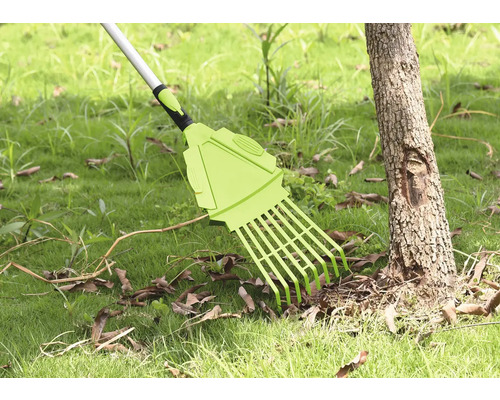 Trädgårdsräfsa för att ta bort löv på gräsmatta bredvid trädstam