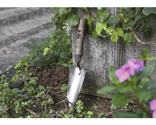 Rostfri sked med trähandtag i en trädgårdsbädd