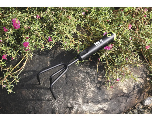 Trädgårdskultivator på en sten bland växter