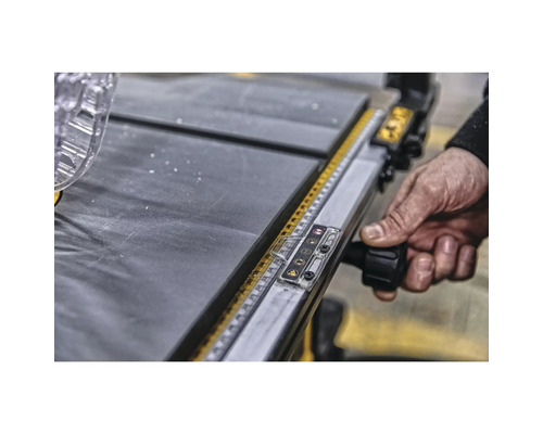 Detaljbild av en bordssåg med en hand som manövrerar en justeringsknapp