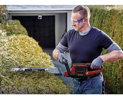 Man klipper häck med en elektrisk häcksax från Einhell.