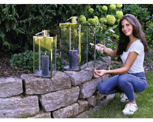 Kvinna tänder ljus i lykta i trädgården