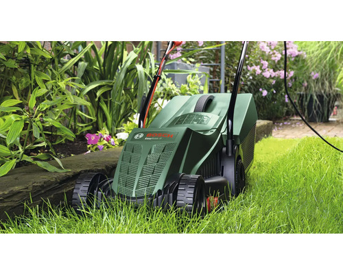 Gräsklippare i användning i trädgården mellan växterna